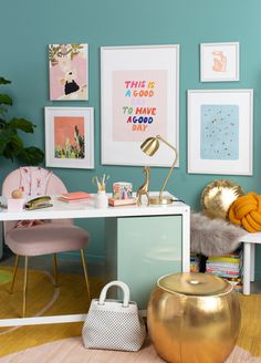 a desk with pictures on the wall above it and a gold stool next to it