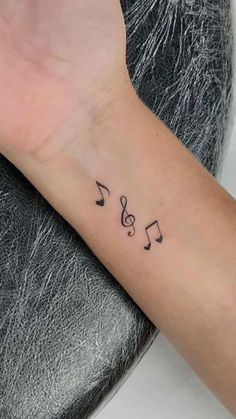 a wrist tattoo with musical notes on it