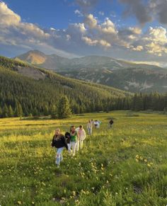 group of people walking in grassy field with mountains in the background