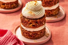 three cupcakes with white frosting and toppings on them sitting on plates