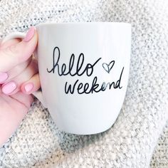 a woman's hand holding a coffee mug with the words hello weekend written on it