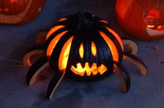 three pumpkins with carved faces on them sitting in front of some jack - o'- lanterns