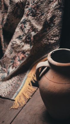 a brown pot sitting on top of a wooden floor next to a rug and blanket