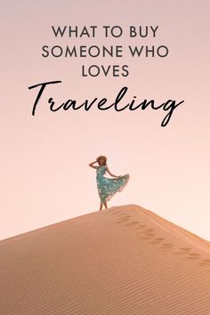 a woman standing on top of a sand dune with text overlay that reads, what to buy someone who loves traveling