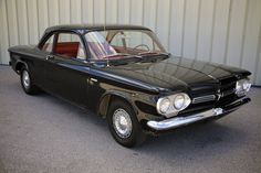 an old black car parked in front of a building