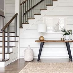 a room with white walls and wood floors has a rug on the floor next to a wooden table