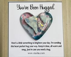 a heart shaped brooch sitting on top of a piece of paper with the words you've been hugged