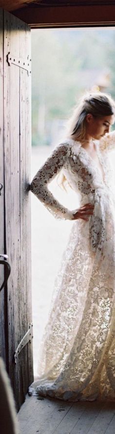 a woman in a white dress is standing by a door