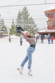 a woman is in the snow with her arms out and one hand up as she skates