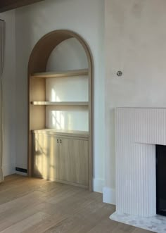 an empty living room with a fireplace and shelves