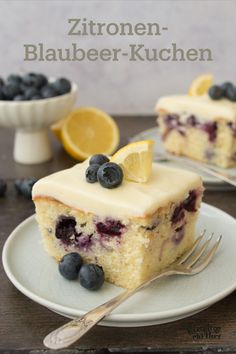 a slice of blueberry cake on a plate with a fork and bowl of lemons in the background