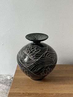 a black vase sitting on top of a wooden table