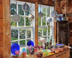 a kitchen counter topped with lots of colorful dishes and plates next to a large window