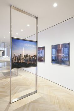 an empty room with two pictures on the wall and one in front of it's glass display