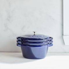 a stack of blue pots sitting on top of a counter next to a white wall