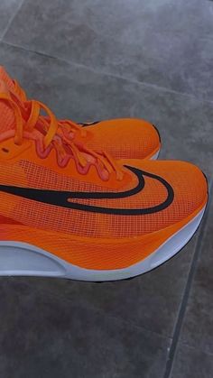 an orange and black nike shoe is on the ground in front of a tile floor