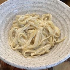 a white bowl filled with pasta on top of a wooden table