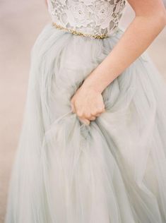 a woman in a gray dress is holding her hand on her waist and wearing a gold belt