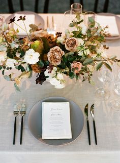 the table is set with flowers and silverware