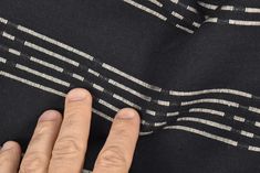 a person's hand on the side of a black and white striped fabric