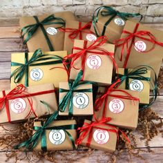 small brown boxes with green and red ribbons tied around them on a wooden table next to dried grass