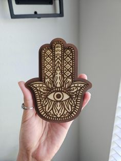 a person holding up a wooden hamsa with an evil eye on it's face