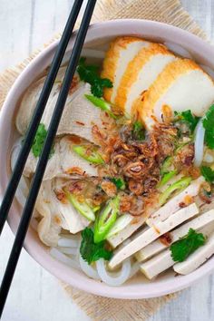 a bowl filled with meat and vegetables next to chopsticks