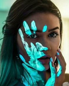 a woman with blue paint on her face and hands painted to look like hand prints