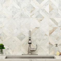 a kitchen sink sitting under a faucet next to a tiled wall