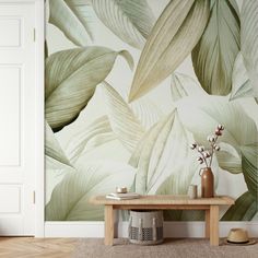 a table with vases and flowers on it in front of a large wall mural