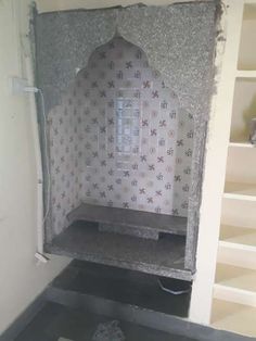 an unfinished room with white walls and grey tile on the floor, in front of a bookshelf