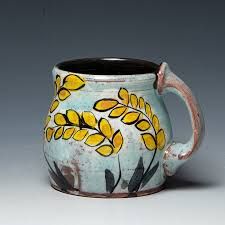 a ceramic mug with yellow flowers painted on the outside and black inside, sitting on a white surface