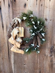 a wreath with pine cones and white flowers hanging on a wooden wall next to a pair of scissors