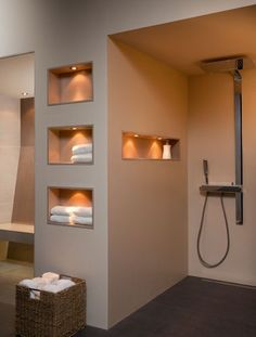 a modern bathroom with white towels on the shelf and shower head in the corner,