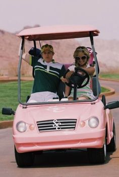 two people riding in a pink golf cart