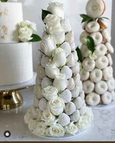 three cakes decorated with white flowers on top of a table next to eachother