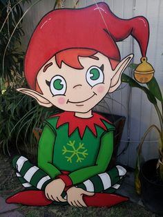 an elf sitting on the ground next to a potted plant