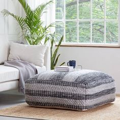 a living room with a white couch, blue and white ottoman and potted plant