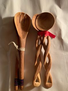 two wooden spoons, one with a red ribbon and the other made out of wood