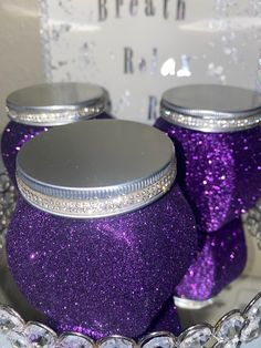 two purple jars with silver lids are sitting in a bowl