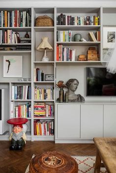 a living room filled with lots of books and furniture next to a flat screen tv