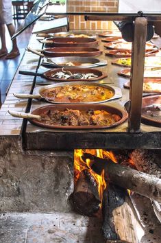 many plates of food are cooking over an open fire