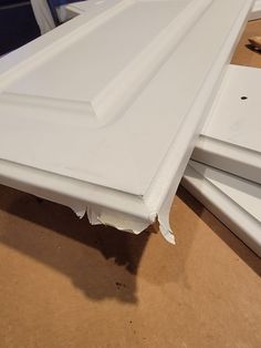 three pieces of white painted wood sitting on top of a wooden table next to each other