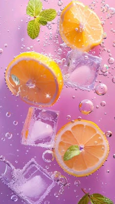 three lemons, one orange and two mint leaves on ice cubes with water droplets