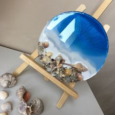 there is a blue bowl with seashells in it on a stand next to other shells