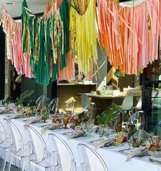 a long table with many different colored streamers hanging from it's ceiling and chairs around it