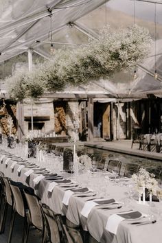 the tables are set up for an outdoor wedding reception with white flowers and greenery