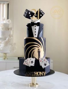 a black and gold wedding cake with playing cards on top