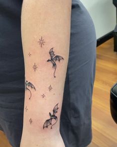 a woman's arm with three flying birds and stars tattoo on the left forearm