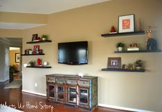 a flat screen tv sitting on top of a wooden entertainment center next to a wall